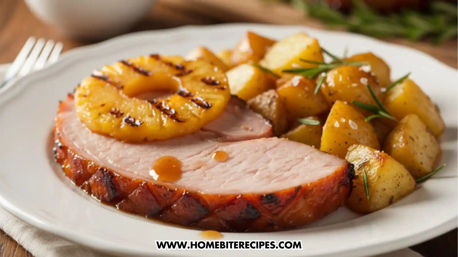 Close up of a slice of Hot Honey Glazed Ham served with Roasted potatoes with rosemary on a white elegant dish