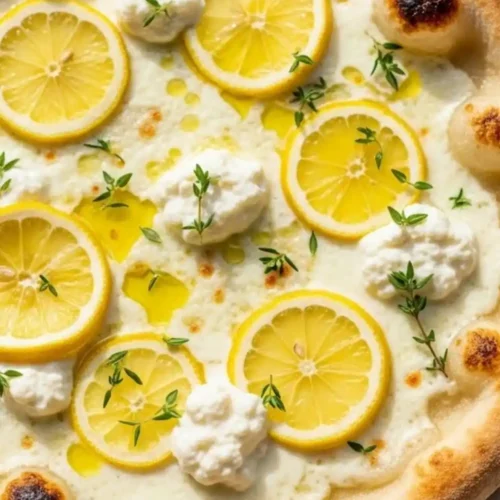Lemon ricotta pizza topped with thin lemon slices, fresh thyme, olive oil, and creamy ricotta on a golden crispy crust.