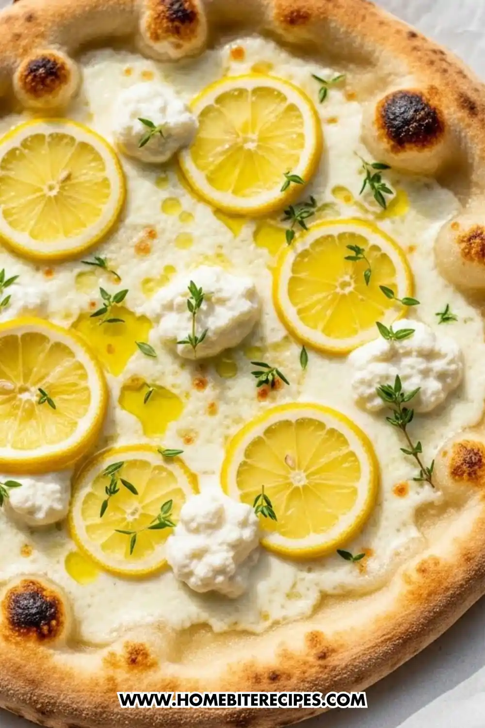 Lemon ricotta pizza topped with thin lemon slices, fresh thyme, olive oil, and creamy ricotta on a golden crispy crust.