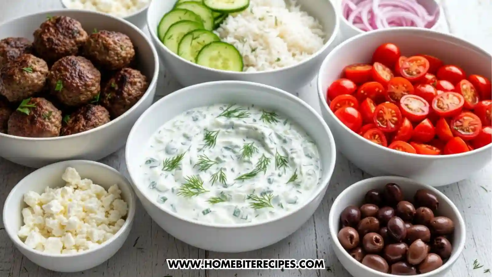 Bowls of Mediterranean ingredients including juicy cooked meatballs, creamy tzatziki with fresh dill, sliced cucumbers, fluffy white rice, cherry tomatoes, pickled red onions, feta cheese, and Kalamata olives arranged on a table for assembling Mediterranean meatball bowls."