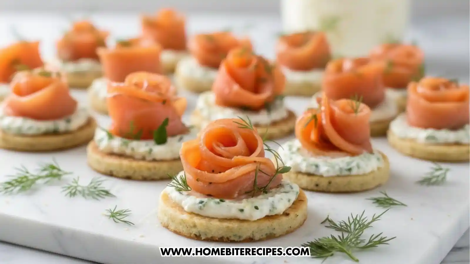 Close-up view of elegant smoked salmon rose canapés arranged on a marble surface, featuring thin slices of smoked salmon shaped into roses on top of herb cream cheese and round crackers, garnished with fresh dill.