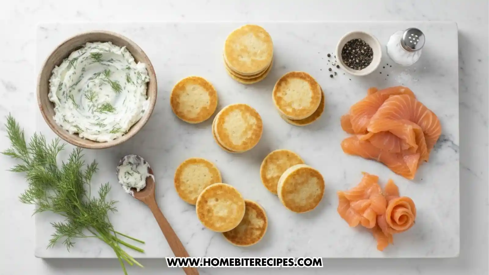 Overhead view of ingredients for smoked salmon canapés arranged on a marble board, including a bowl of herb cream cheese, fresh dill, stacks of round toasted crackers, black pepper, salt, and thin slices of smoked salmon ready to be shaped into roses.