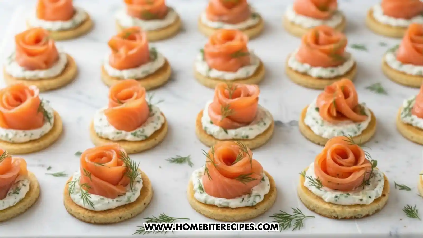 Close-up view of elegant smoked salmon rose canapés arranged on a marble surface, featuring thin slices of smoked salmon shaped into roses on top of herb cream cheese and round crackers, garnished with fresh dill.