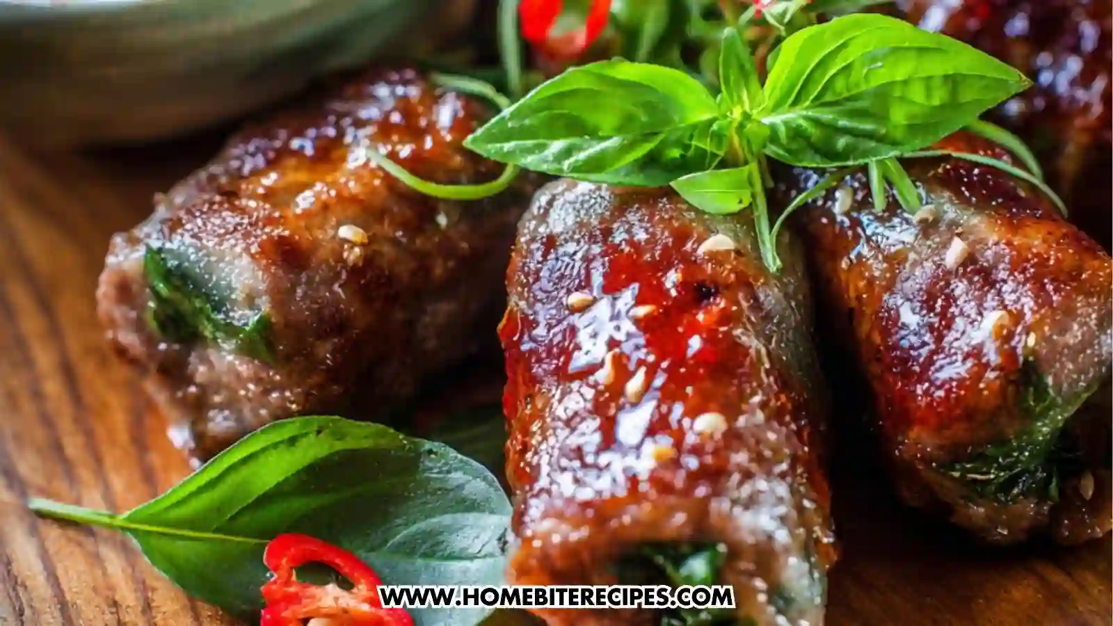 Close-up of Vietnamese basil beef rolls filled with crisp cabbage and beef, with a bowl of spicy chili dipping sauce on a wooden platter.