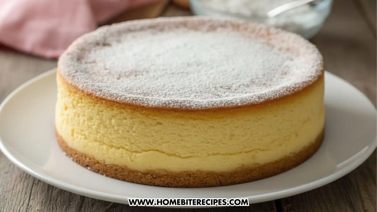A fluffy Japanese cheesecake with a soft golden top, dusted with powdered sugar, with one slice removed and displayed on a spoon showing its light and airy interior.