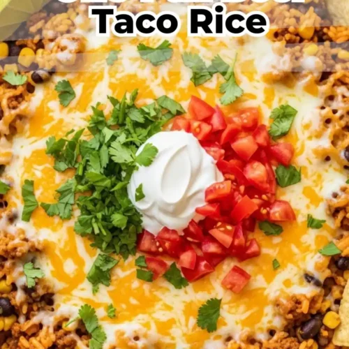 One-pan beef taco rice skillet with melted cheese, black beans, and corn, topped with sour cream, tomatoes, and cilantro.
