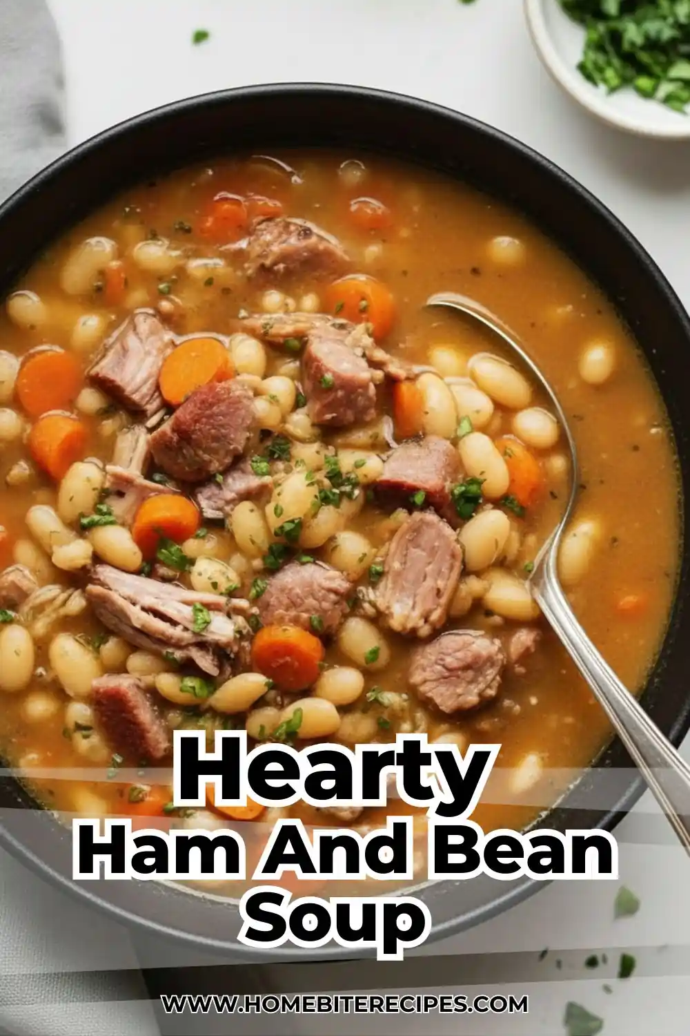 Close-up of a bowl filled with thick ham and bean soup, featuring white beans, ham pieces, and carrots garnished with parsley.