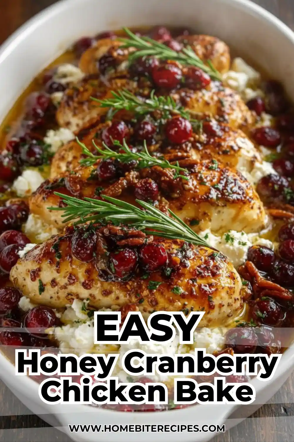 A vertical top-down shot of a white baking dish containing honey-glazed chicken breasts, whole roasted cranberries, pecans, and dollops of white ricotta cheese, garnished with fresh rosemary